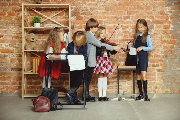 Grupo de niños que pasan tiempo juntos después de la escuela. Amigos guapos descansando después de clases antes de comenzar a hacer los deberes. Interior de loft moderno. Horario escolar, amistad, educación, concepto de unión.