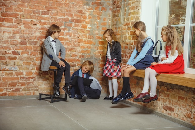 Grupo de niños que pasan tiempo juntos después de la escuela. Amigos guapos descansando después de clases antes de comenzar a hacer los deberes