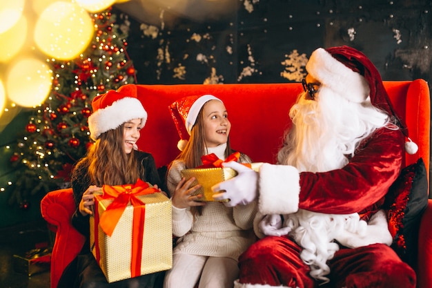 Grupo de niños sentados con santa y regalos en la víspera de Navidad