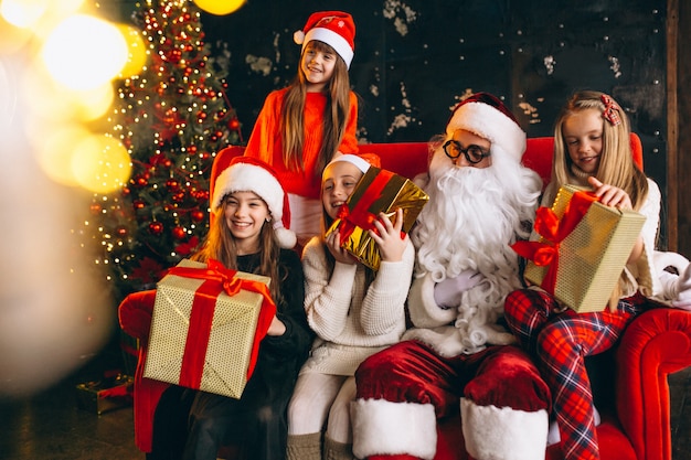 Grupo de niños sentados con santa y regalos en la víspera de Navidad