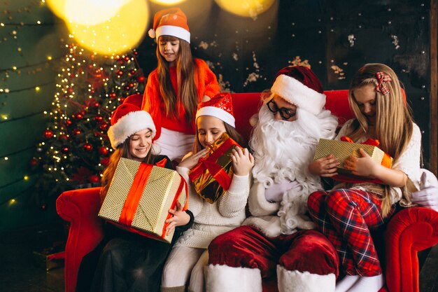 Grupo de niños sentados con santa y regalos en la víspera de Navidad