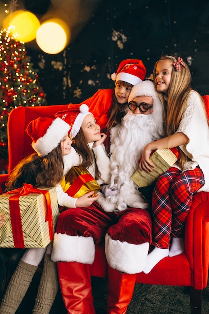 Grupo de niños sentados con santa y regalos en la víspera de Navidad