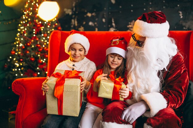 Grupo de niños sentados con santa y regalos en la víspera de Navidad