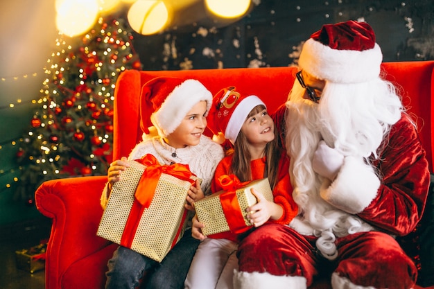 Grupo de niños sentados con santa y regalos en la víspera de Navidad