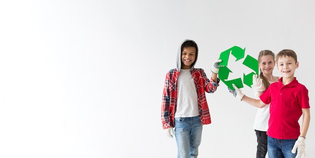 Grupo de niños sonrientes con cartel de reciclaje