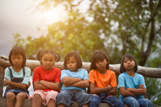 Grupo de niños tristes que se sientan en el parque