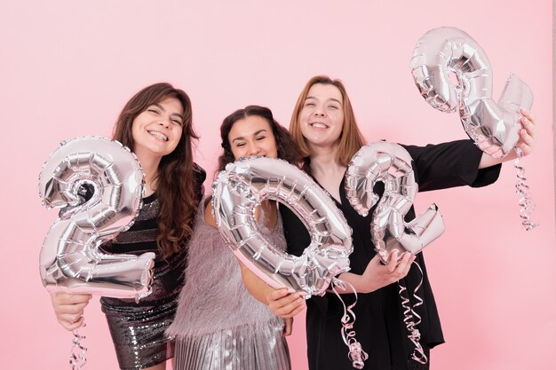 Un grupo de novias con globos plateados en forma de números.