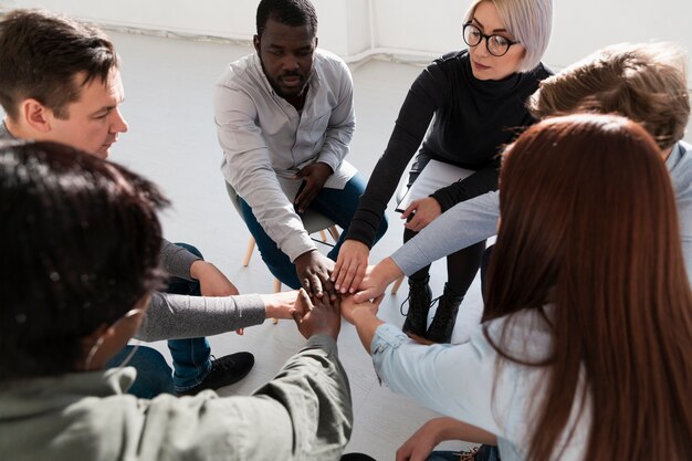 Grupo de pacientes de rehabilitación juntando sus manos