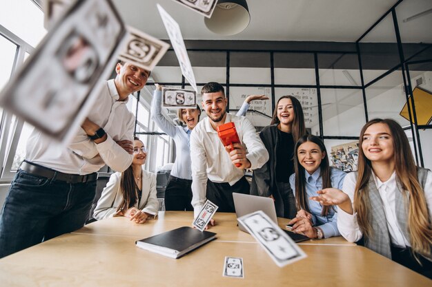 Grupo de personas arrojando dinero en una oficina