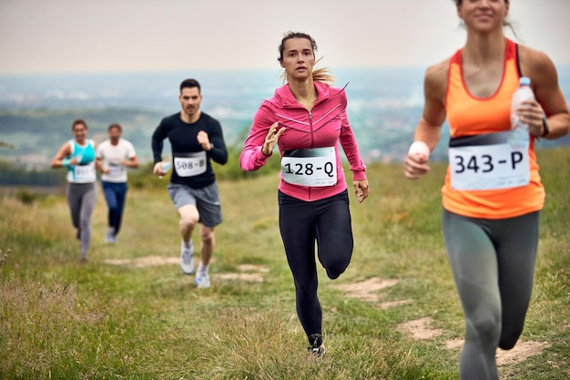 Grupo de personas atléticas corriendo maratón en la naturaleza El foco está en la mujer joven