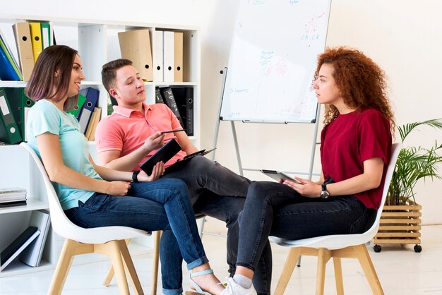 Grupo de personas discutiendo en la sala de estudio mientras sostiene la tableta digital y el portapapeles