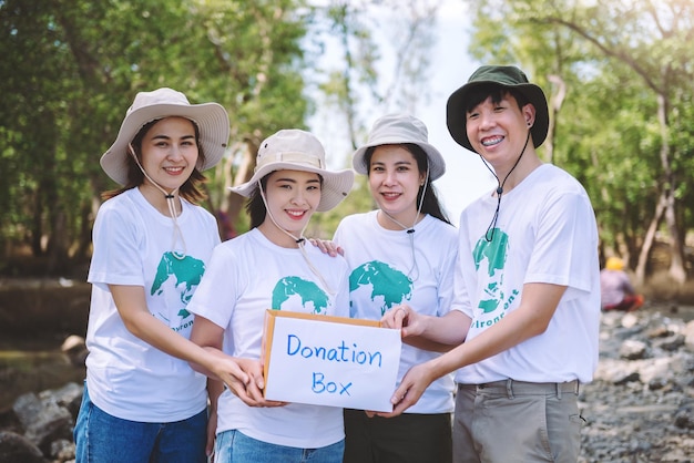 Grupo de personas diversas asiáticas voluntarias que sostienen una caja de donación para recaudar fondos para situaciones de emergencia, como ayudar a las víctimas de las inundaciones en Ucrania, comida para niños, evento de caridad Voluntariado conceptual