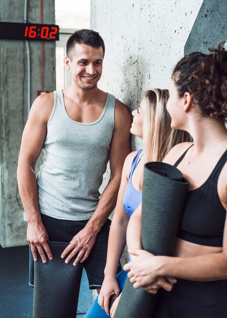 Grupo de personas felices con estera de ejercicio en el gimnasio