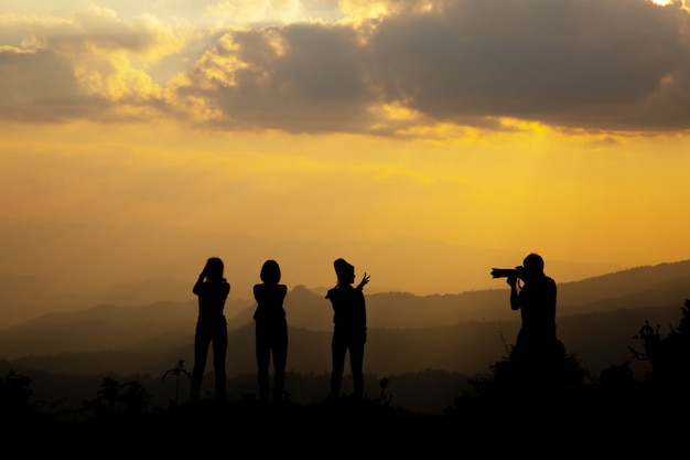 Grupo de personas felices fotografiando en la montaña al atardecer