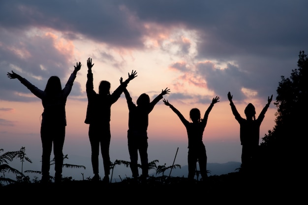 Grupo de personas felices jugando al atardecer de verano en la naturaleza