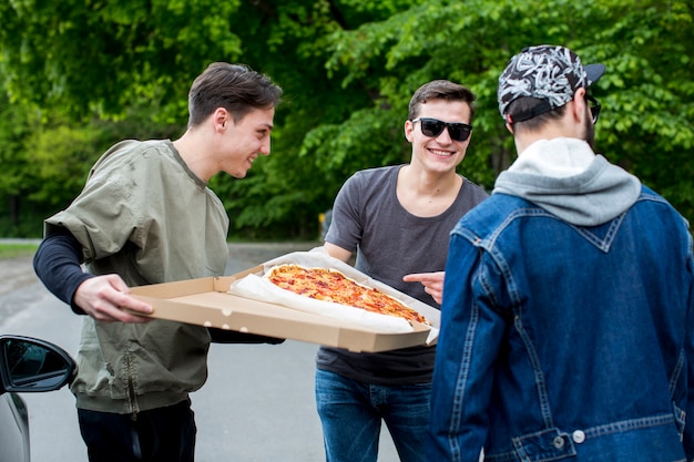 Foto gratuita grupo de personas felices que van a comer pizza en la naturaleza