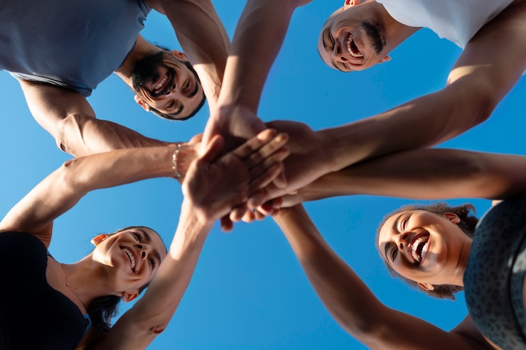 Foto gratuito grupo de personas juntando las manos mientras hacen ejercicio al aire libre