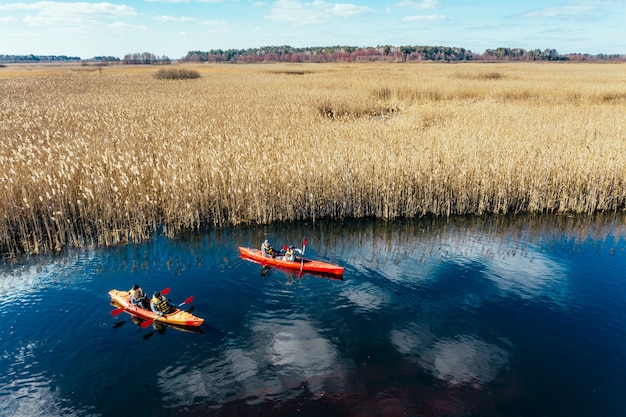 Grupo de personas en kayaks entre cañas en el río de otoño.