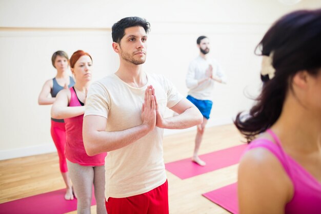 Grupo de personas que realizan ejercicio de yoga árbol-pose