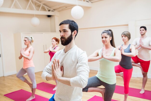 Grupo de personas que realizan ejercicio de yoga árbol-pose