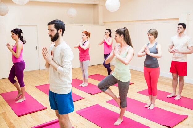 Grupo de personas que realizan ejercicio de yoga árbol-pose