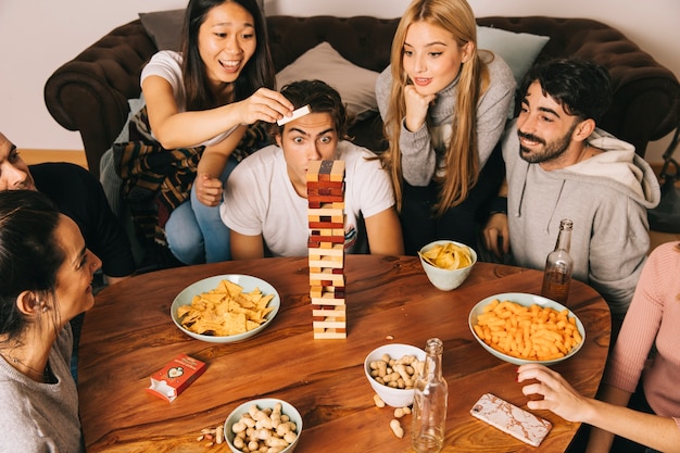 Grupo de seis amigos felices jugando juego de mesa