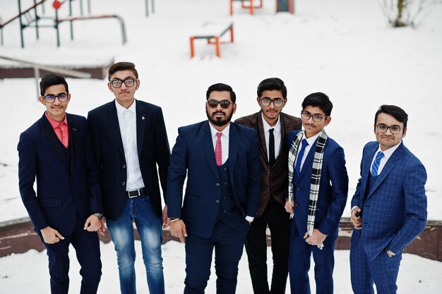 Grupo de seis hombres de negocios indios en trajes posados al aire libre en un día de invierno en Europa