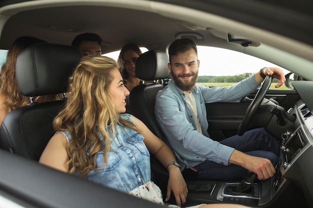 Grupo sonriente de amigos que viajan en coche