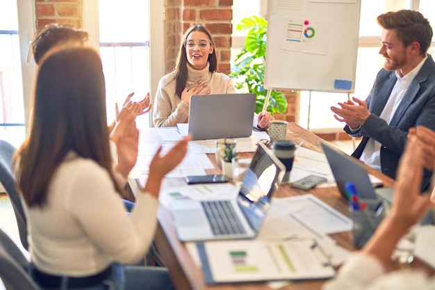 Foto gratuita grupo de trabajadores de negocios sonriendo felices y confiados trabajando juntos con una sonrisa en la cara aplaudiendo a uno de ellos en la oficina