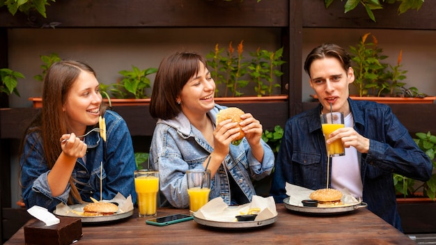 Grupo de tres amigos comiendo hamburguesas