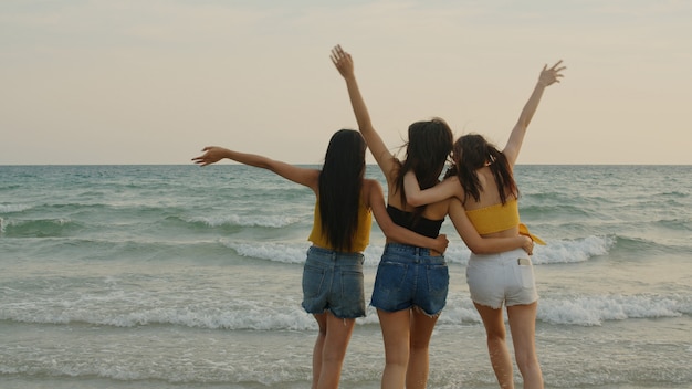 Grupo de tres mujeres jóvenes asiáticas caminando en la playa
