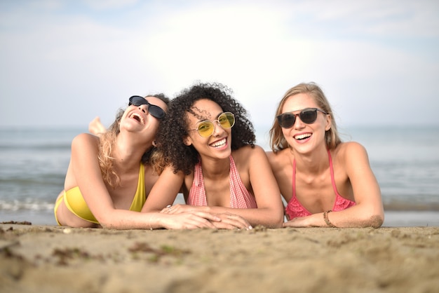 Grupo de tres mujeres jóvenes sonrientes en la playa, el concepto de felicidad