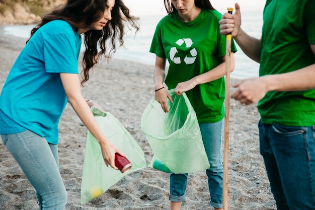 Foto gratuita grupo de tres voluntarios recogiendo basura en la playa