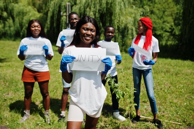 Grupo de voluntarios africanos felices sostienen un tablero en blanco con un cartel de unidad en el parque África voluntariado personas caritativas y concepto de ecología