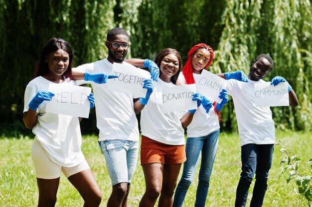 Grupo de voluntarios africanos felices sostienen un tablero en blanco en el parque África voluntariado personas caritativas y concepto de ecología
