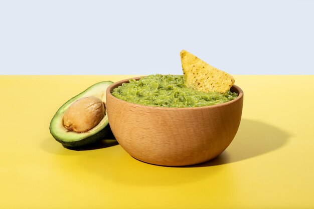 Guacamole mexicano con nacho chip sobre fondo amarillo