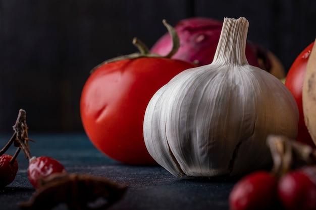 Guantes de ajo y tomates en mesa negro.