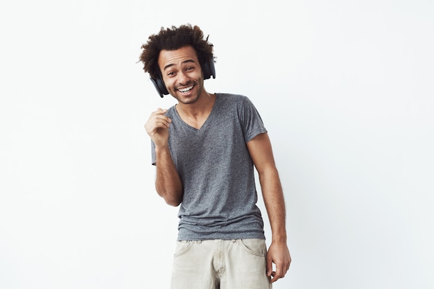 Foto gratuita guapo alegre hombre africano en auriculares riendo. aislado en