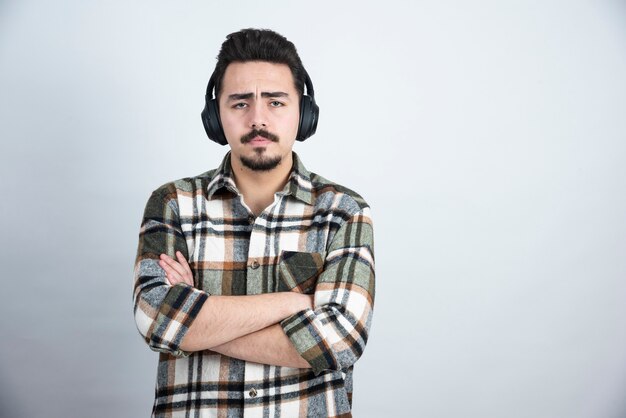 guapo en auriculares escuchando música sobre pared blanca.