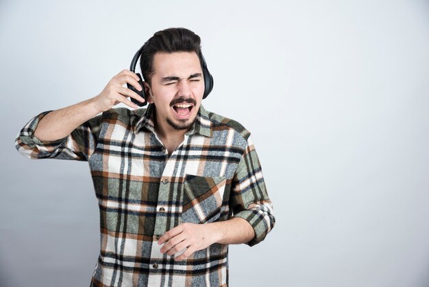 guapo en auriculares de pie y escuchando la canción.