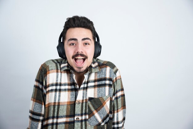 guapo en auriculares de pie y posando para la cámara.