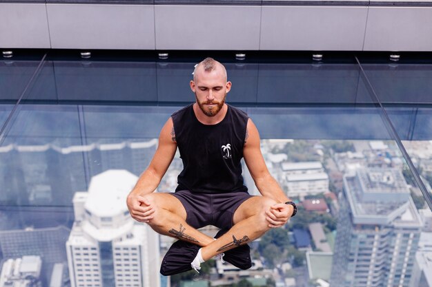 Guapo brutal hombre caucásico barbudo sobre piso de vidrio rd en Bangkok