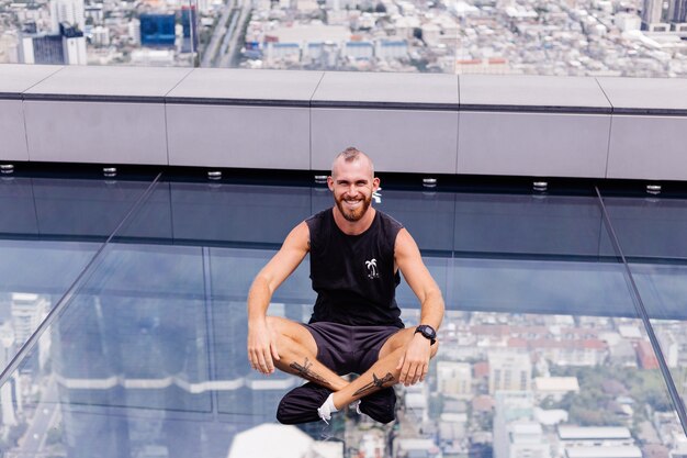 Guapo brutal hombre caucásico barbudo sobre piso de vidrio rd en Bangkok