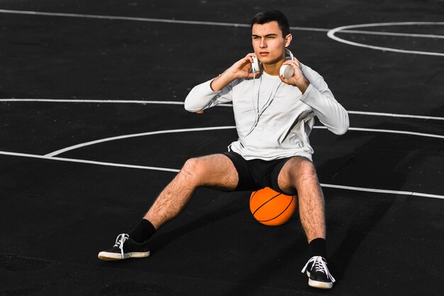 Guapo deportista sentado en baloncesto