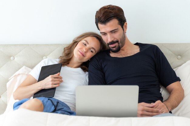 guapo esposo y hermosa esposa se sienten pareja romántica viendo películas desde la computadora portátil en la habitación