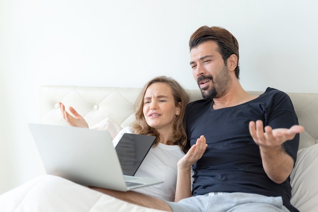 guapo esposo y hermosa esposa se sienten pareja romántica viendo películas desde la computadora portátil en la habitación
