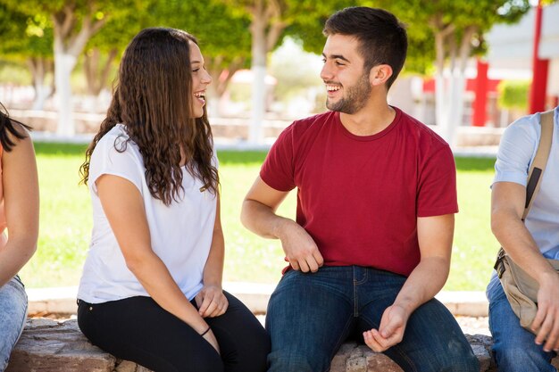 Guapo estudiante universitario hablando y coqueteando con una chica en la escuela