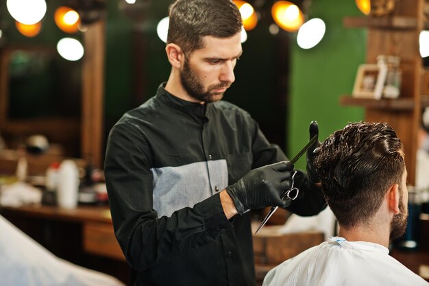 Guapo hombre barbudo en la barbería peluquero en el trabajo