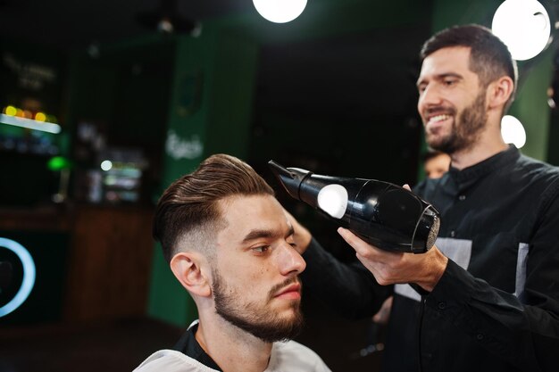 Guapo hombre barbudo en la barbería peluquero en el trabajo