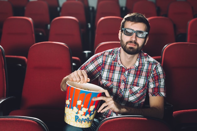 Foto gratuita guapo hombre comiendo palomitas de maíz durante la película